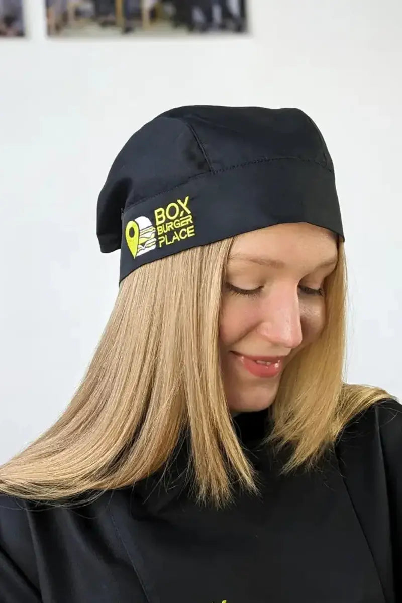 Woman wearing a black chef bandana with an embroidered company logo