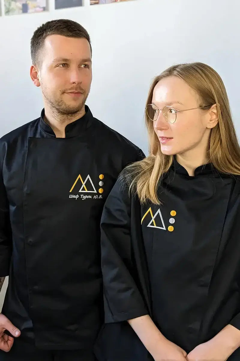 Restaurant staff wearing black chef jackets with embroidered company logos