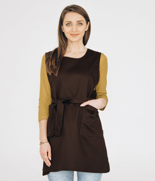 A person wearing a brown double-sided tunic apron with a tie around the waist and different colored sleeves.