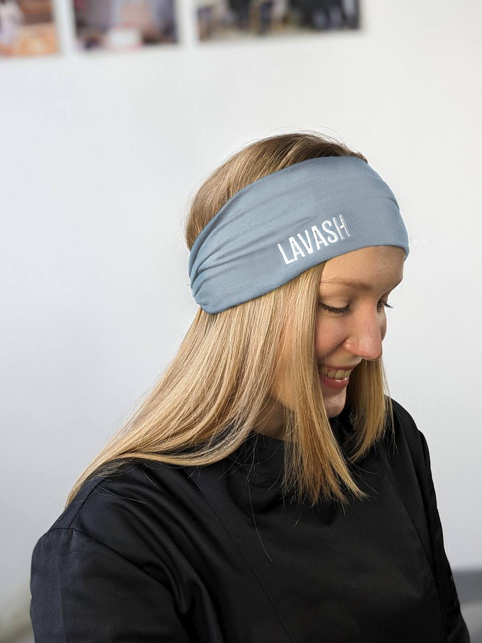 A person wearing a grey headband with the text 'KITCHEN' on it, in a kitchen setting.