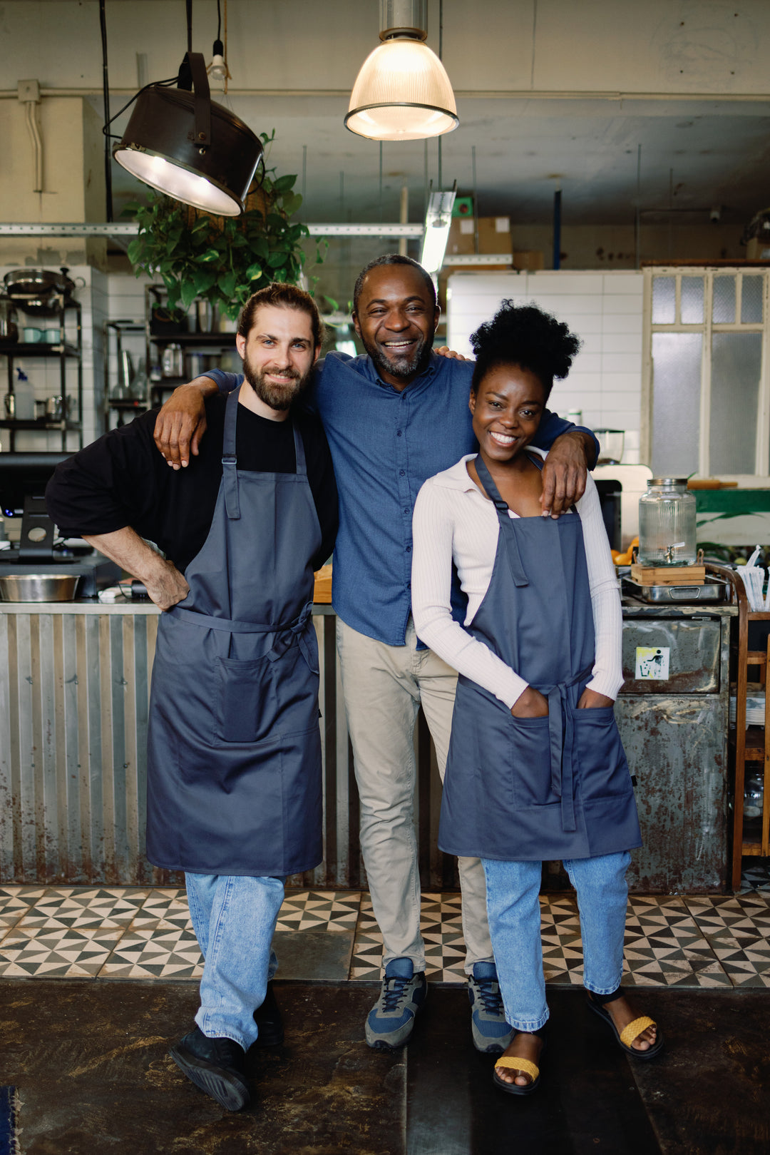 Restaurant staff wearing dark gray bib aprons in a café kitchen