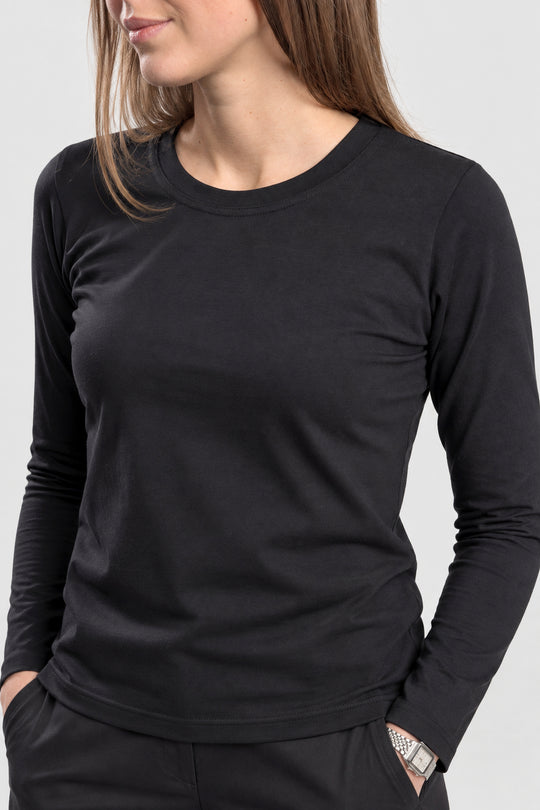 A woman wearing a plain black long-sleeve crewneck top, cropped from the chin down against a light gray studio background.