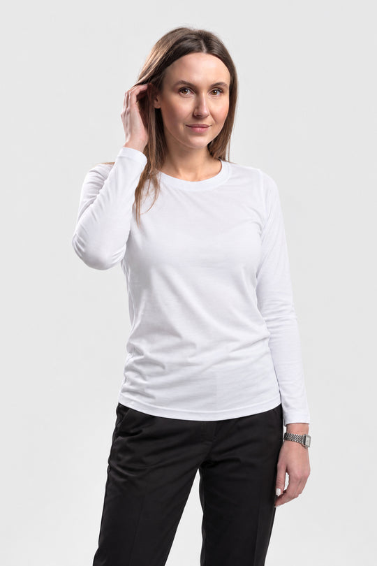 A woman modeling a white long-sleeve crewneck shirt paired with black pants, standing against a light gray studio background.