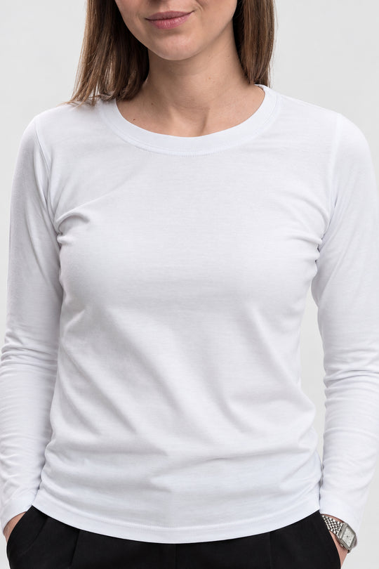 A woman wearing a plain white long-sleeve crewneck t-shirt, cropped from the chin down, against a light gray studio background.
