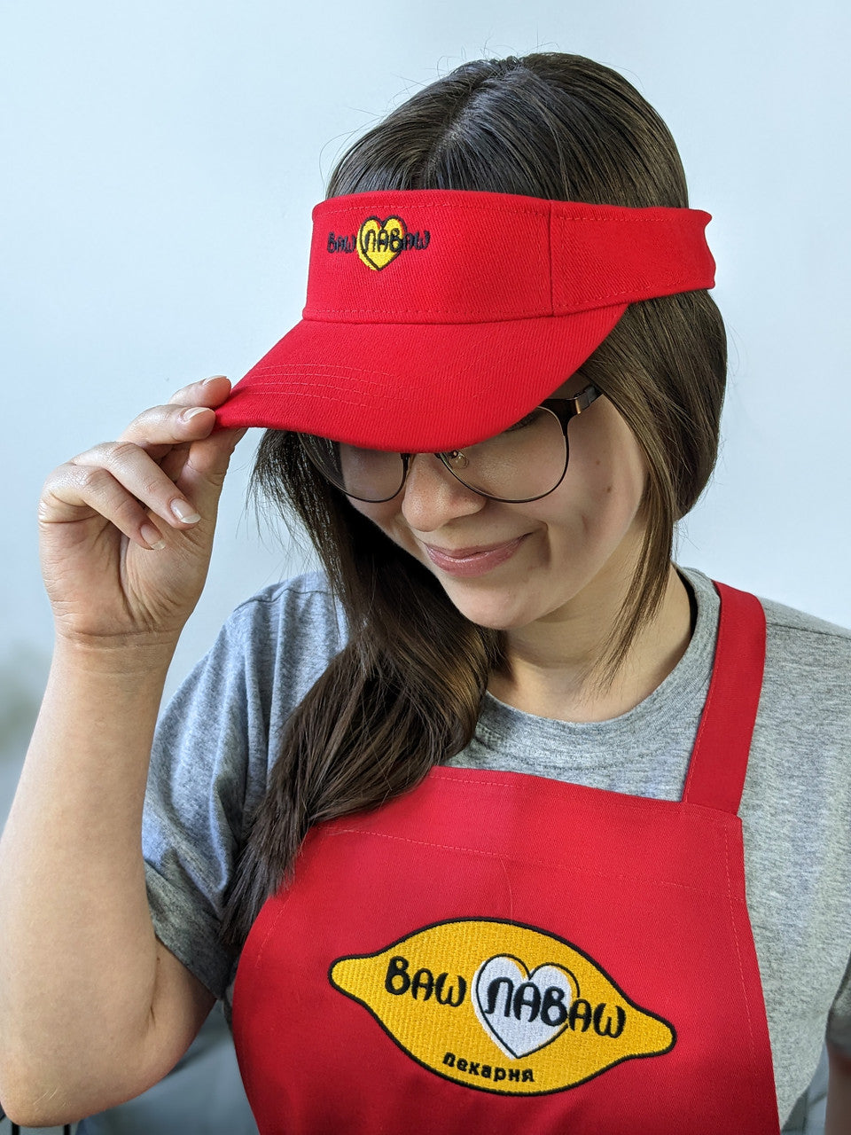 A person wearing a red visor cap with a logo on it.