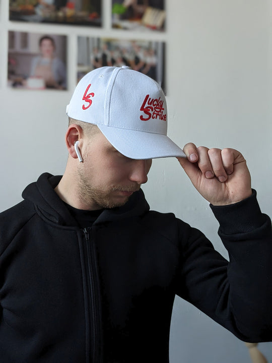 A person wearing a white baseball cap with a logo in red text on the front.