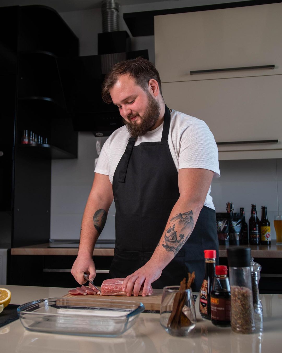 Man wearing a black bib apron while preparing food in a kitchen