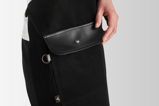 Close-up of black bib apron with large flap pocket, snap closure and metal D-ring