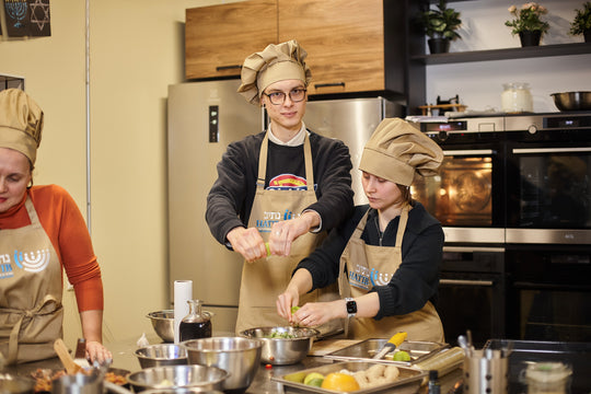 Cooking class participants wearing beige bib aprons with logos and matching chef hats