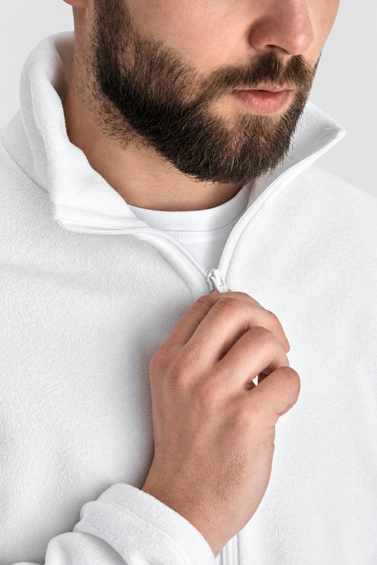 Close-up of a man wearing a white zip-up fleece pullover, pulling the zipper with his hand. The shot focuses on the texture of the white fleece fabric and the collar.