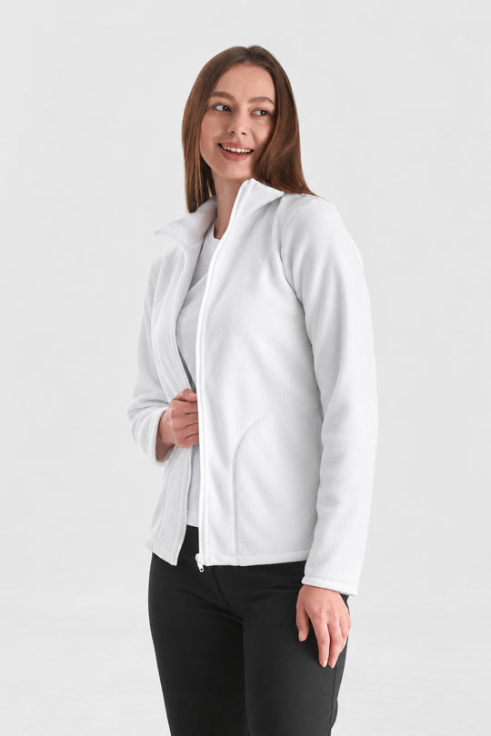 A woman modeling a white zip-up hoodie jacket over a white top and black pants, standing against a light gray studio background.