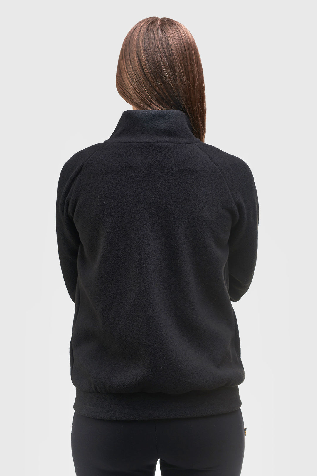 A woman viewed from the back wearing a black long-sleeve quarter-zip fleece jacket and black leggings against a light gray studio background.