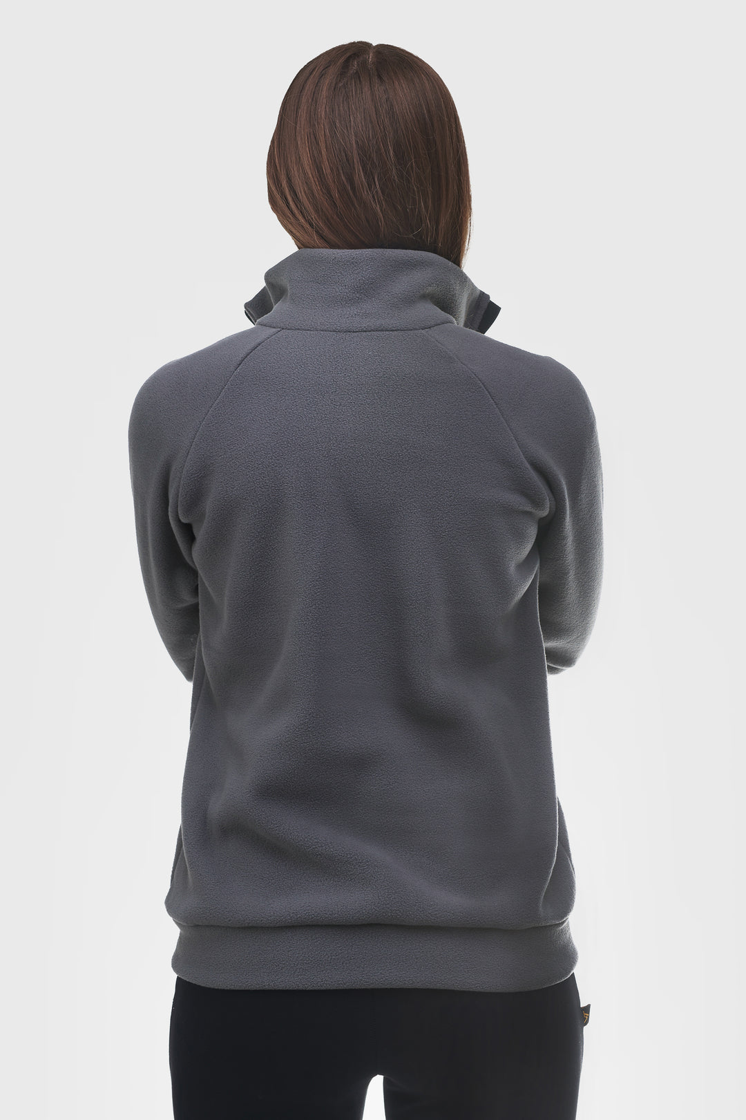 A person shown from the back wearing a dark gray quarter-zip fleece pullover with a mock neck collar and black pants, against a light gray studio background.