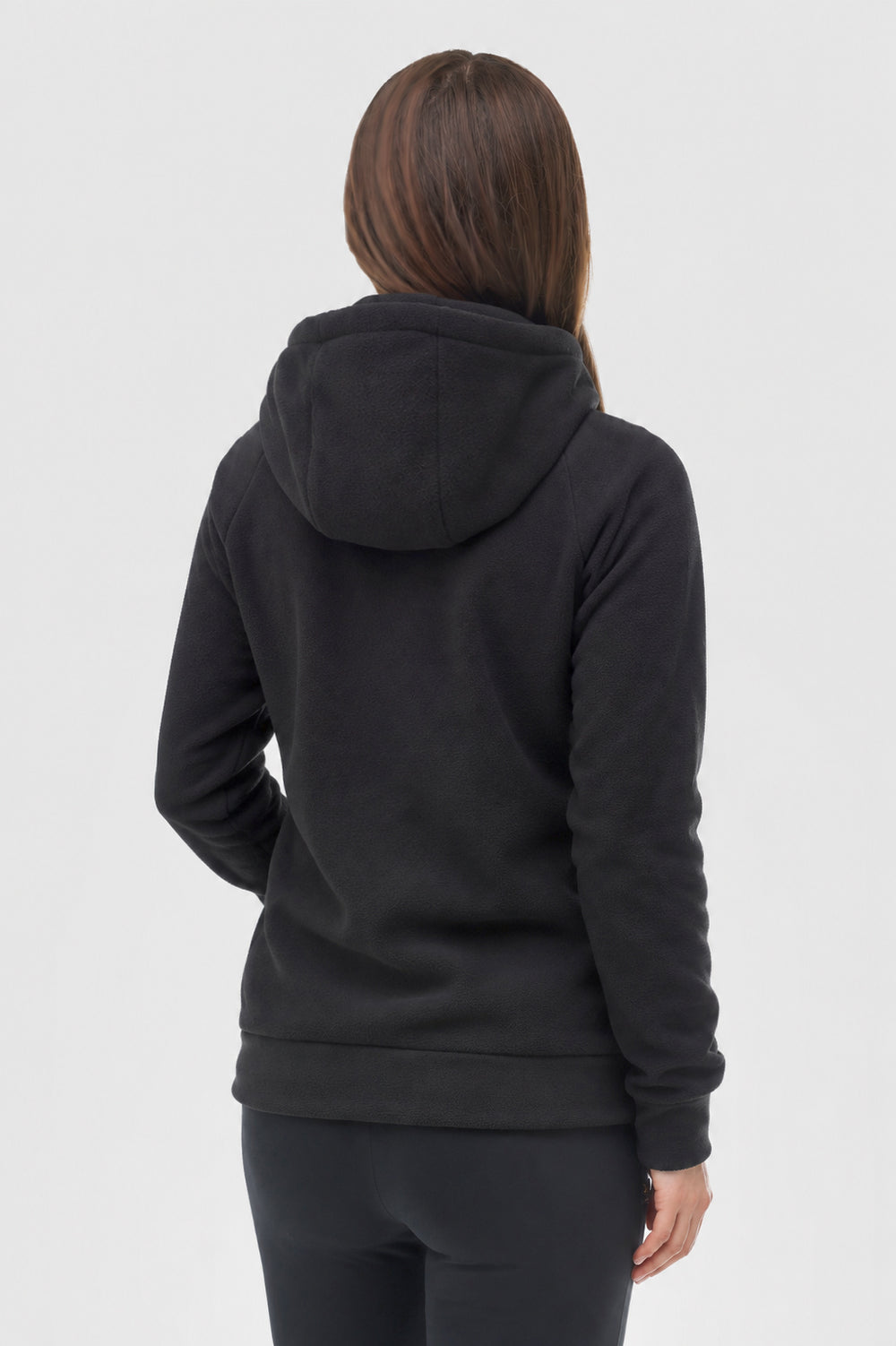 A woman viewed from the back wearing a black pullover hoodie and black leggings against a light gray studio background.