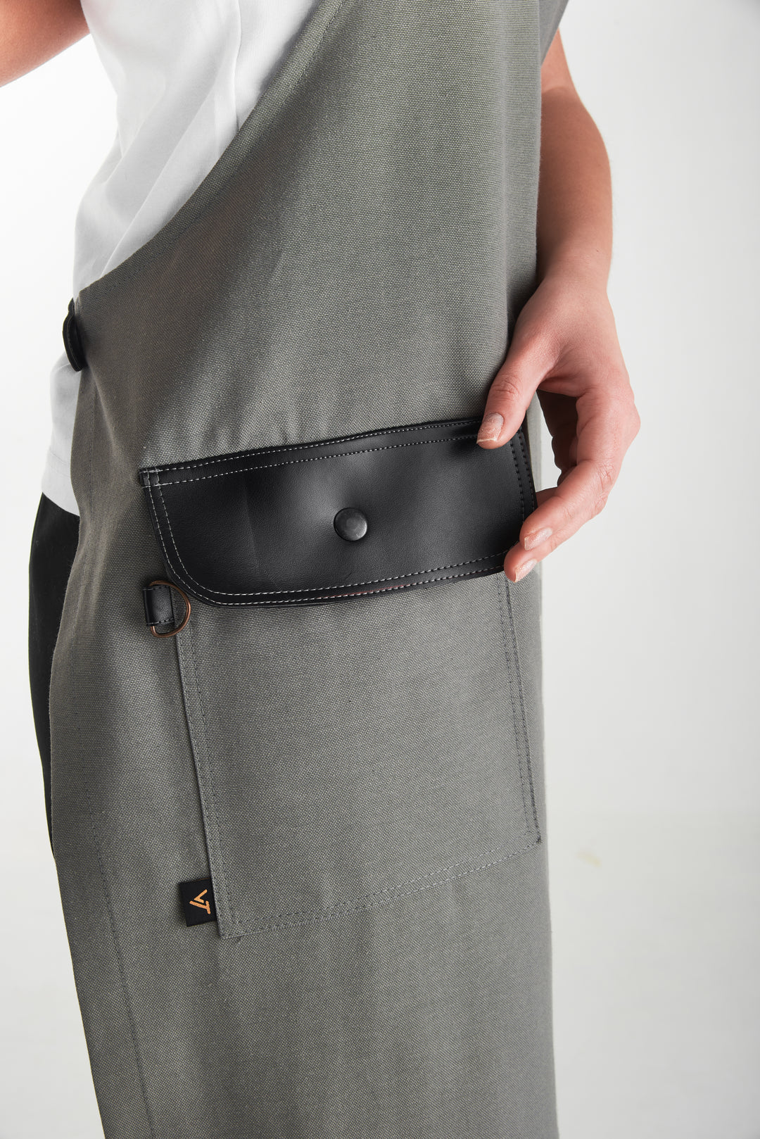 Gray bib apron with black flap pocket and metal snap closure