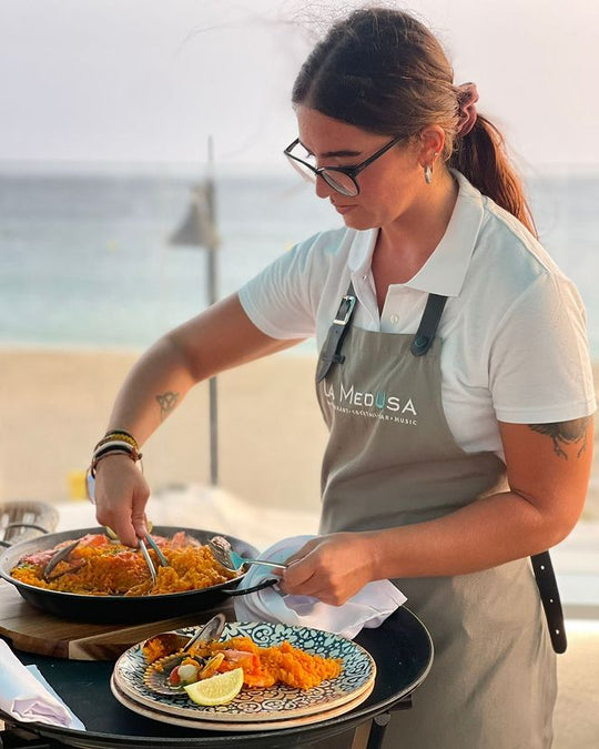 Restaurant staff member wearing a gray bib apron with logo while serving food