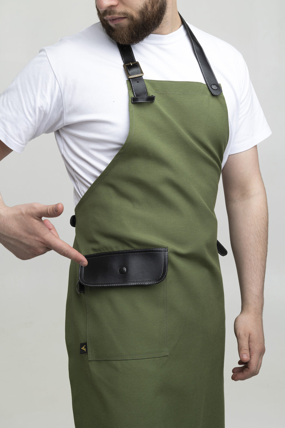 Man wearing a green bib apron with black adjustable straps and flap pocket