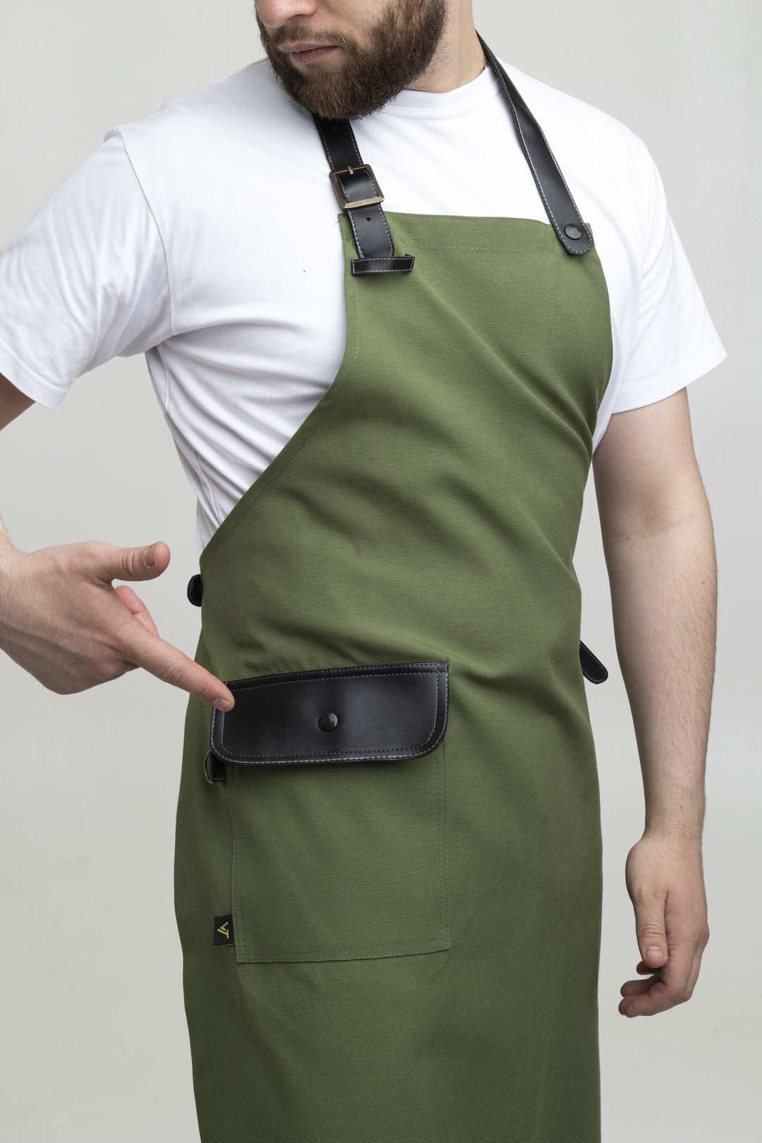 Man wearing a green bib apron with black adjustable straps and flap pocket