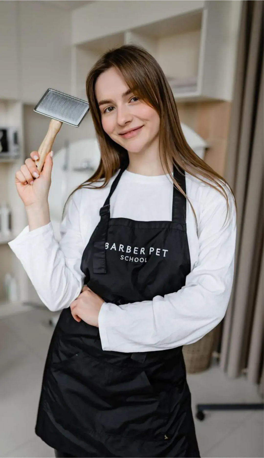 Pet groomer wearing a black apron with embroidered company logo