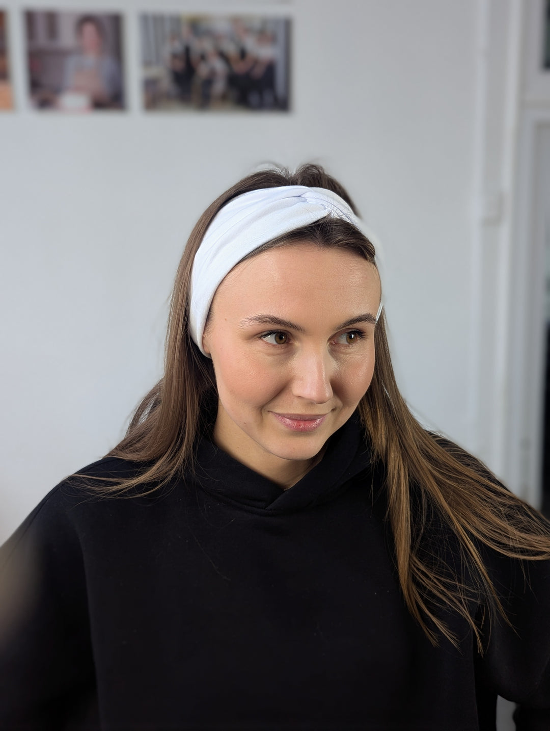 A woman wearing a white headband designed to fit universally on a stretchable fabric base.