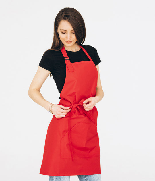 Woman wearing a red bib apron with adjustable neck strap, waist ties and large front pocket