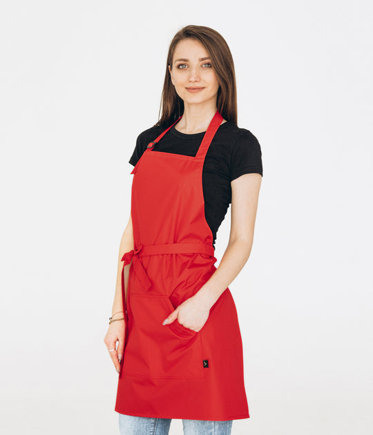 Woman wearing a red bib apron with adjustable neck strap and large front pocket