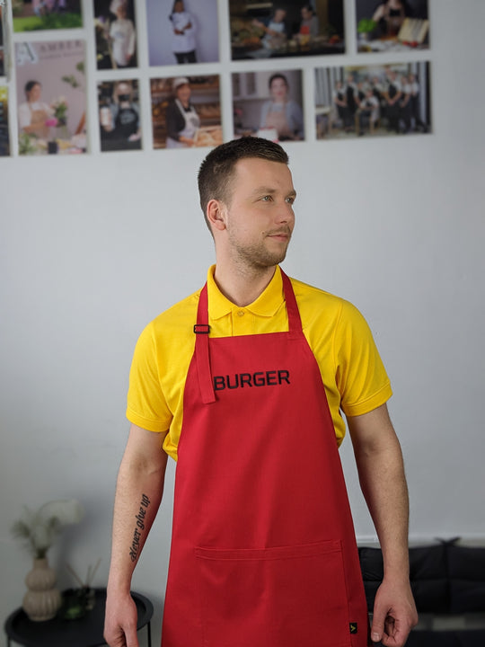 Man wearing a red bib apron with logo for a burger restaurant