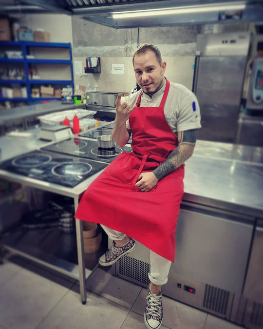 Chef wearing a red bib apron in a professional restaurant kitchen