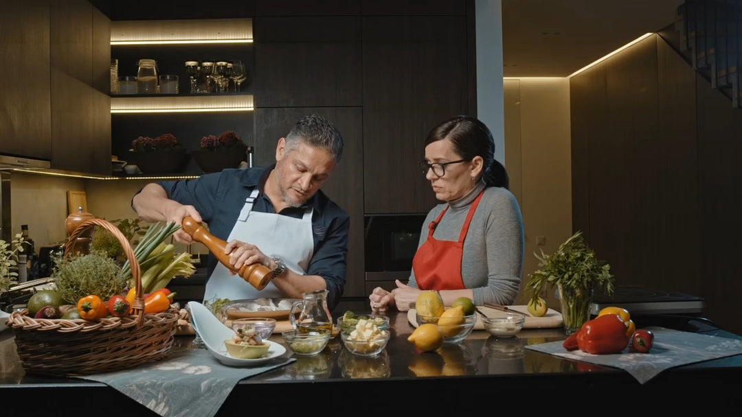 Man and woman wearing professional bib aprons while cooking together in a kitchen