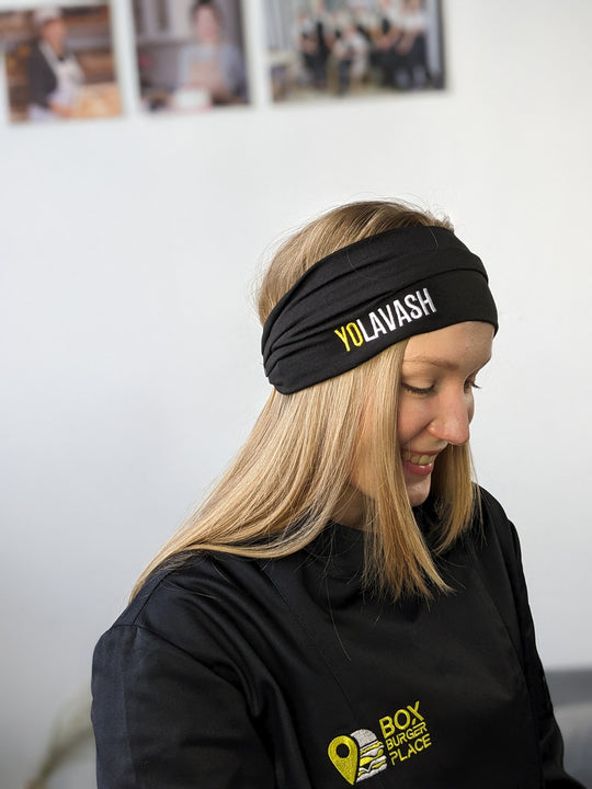 A person wearing a black headband with a logo on it.