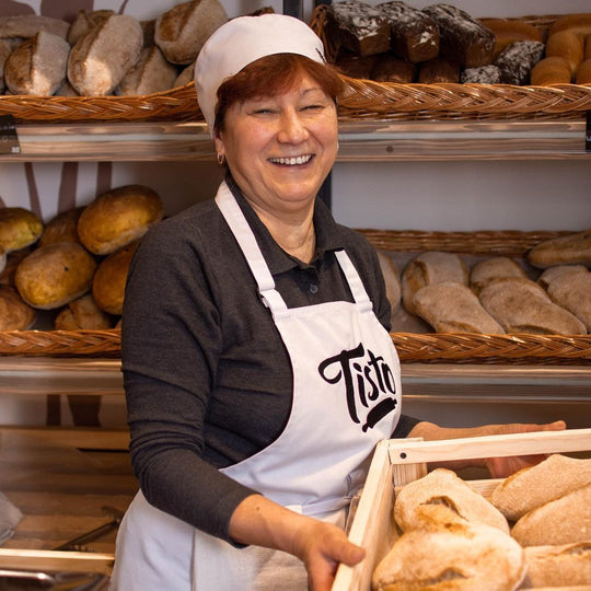 Bakery worker wearing a white bib apron with logo while holding fresh bread