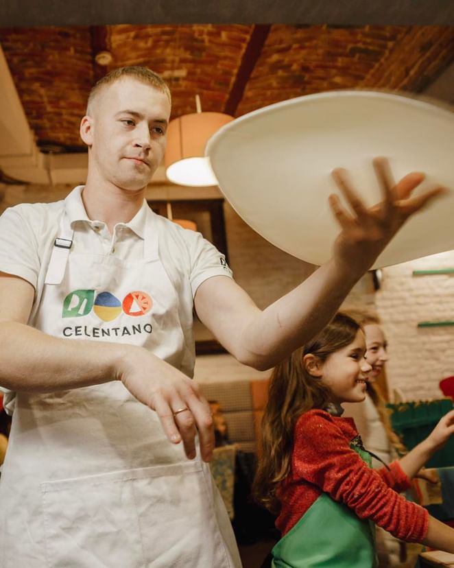 Pizza chef wearing a white bib apron with logo while tossing pizza dough