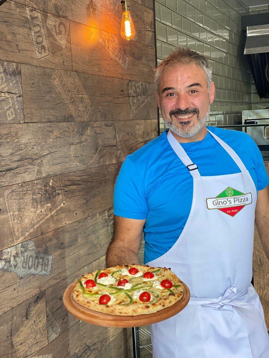 Pizza chef wearing a white bib apron with logo while holding a fresh pizza